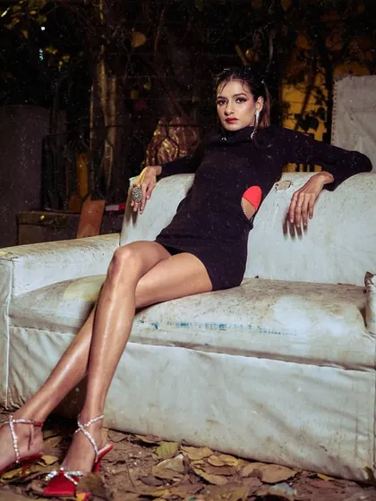 The model is styled in a black cutout dress, seated on a discarded couch for a raw, urban feel in this shot from the 'Embrace Self' portfolio. This shows how to create high fashion looks in unconventional settings.