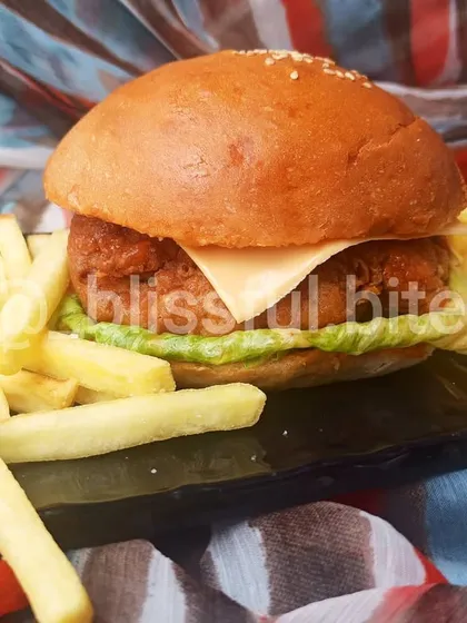 My bestselling Chicken Zinger Burger, featuring a crispy, juicy chicken fillet, fresh lettuce, and a slice of cheese in a soft, homemade bun, served with a side of golden french fries.