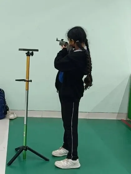 A young shooter stands with perfect form, using a support stand to help stabilize the air rifle. We provide all necessary equipment, including aids for beginners, to ensure a safe and effective learning experience.