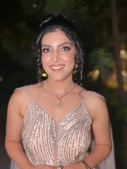 Her smile lights up the frame. The messy bun and soft tendrils add a touch of romance to this glamorous engagement look.