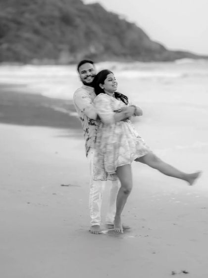 A playful, motion-blur shot of a couple on the beach, capturing their fun and energetic connection in black and white.