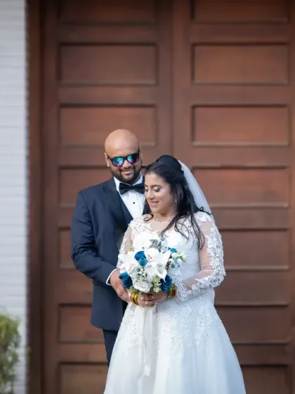 A fun and stylish pose against a modern backdrop. The groom's sunglasses add a cool vibe to this Catholic wedding couple portrait.