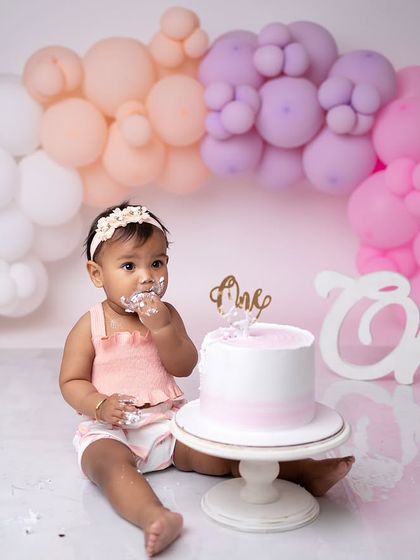 A wider shot showing the beautiful pastel balloon arch and the "One" prop, perfectly framing this first birthday celebration.