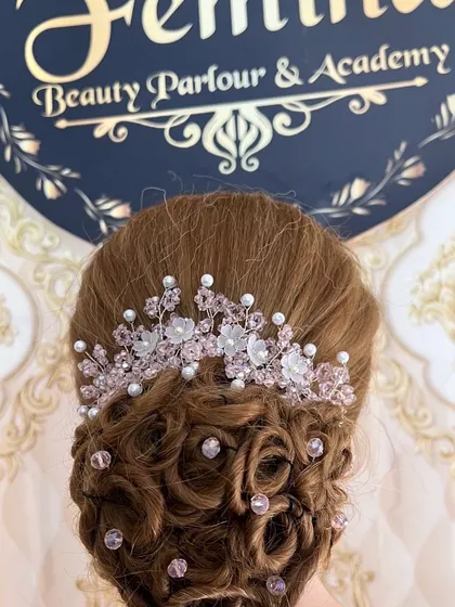 This is an example of the advanced bridal updos we teach. This style features delicate curls pinned into a low bun, accented with a beautiful crystal and pearl hair accessory.