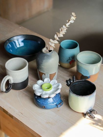 A beautiful assortment of student work from our Jun-Aug cohort, including mugs, bowls, and a small vase, all displaying unique glaze combinations.