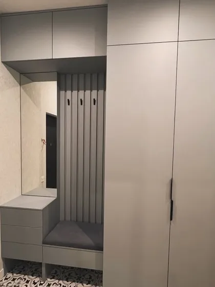 Another view of the integrated wardrobe and entryway bench. The seamless design combines a full-height closet with a practical seating and storage nook, perfect for any modern home.