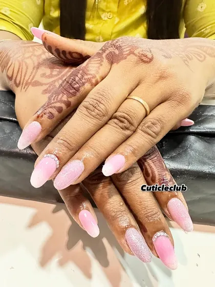 A soft and romantic look featuring a baby pink ombre with a sugar glitter effect. A simple rhinestone detail at the cuticle adds a touch of elegance, making it perfect for an engagement.