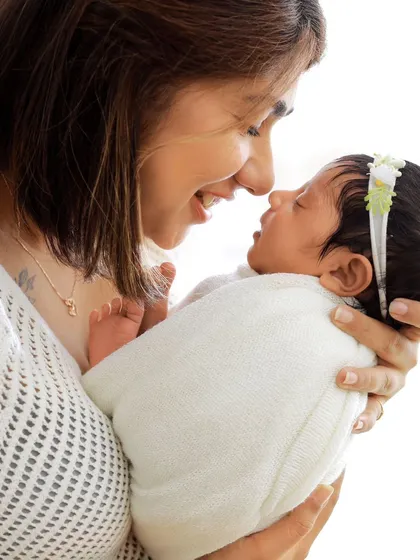 A joyful moment between a mother and her baby. Her bright smile and the gentle way she touches her nose to the baby's shows pure, unscripted love.