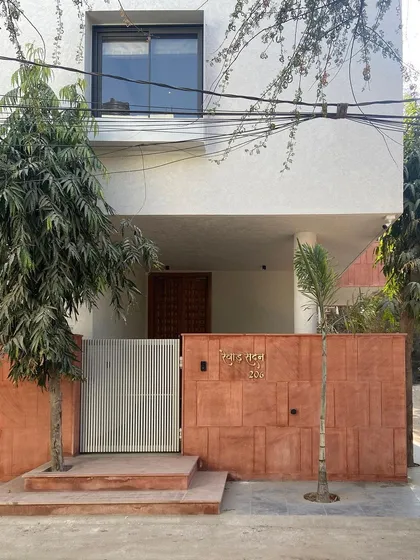 The entrance to the Jaipur House, where a modern gate and simple landscaping complement the traditional red sandstone wall. This view encapsulates the home's dialogue between past and present.