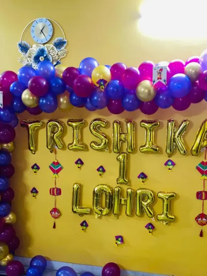 For Trishika's first Lohri, I created this balloon-focused decoration. It features a large balloon arch in purple, pink, and gold, with foil letters spelling out the name and occasion.