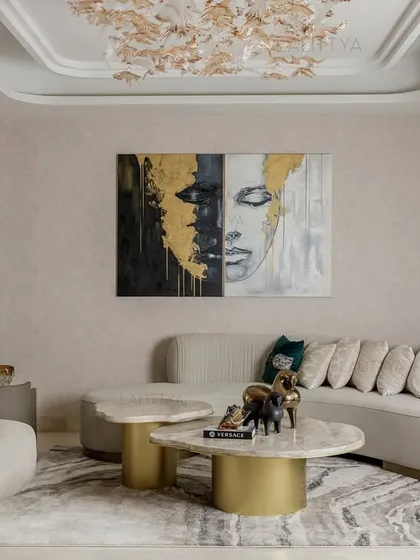 This view showcases the full seating arrangement, designed for conversation and comfort. The mix of a long curved sofa and a sculptural armchair provides varied seating options, all unified by a soft, neutral palette and gold accents.