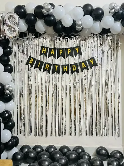 A simple yet classic black and white theme for an 18th birthday at home. This decoration includes a silver fringe curtain, a 'Happy Birthday' banner, and a balloon frame with a number '18' foil balloon.