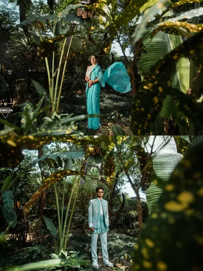 A creative portrait of the couple in a lush, tropical setting, their vibrant outfits standing out against the greenery.
