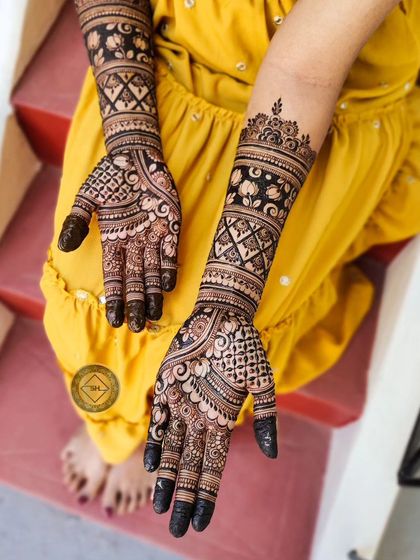 The completed bridal henna for Deepa. The design combines bold, dark floral bands with fine, intricate line work on the palms and fingers for a balanced and beautiful look.
