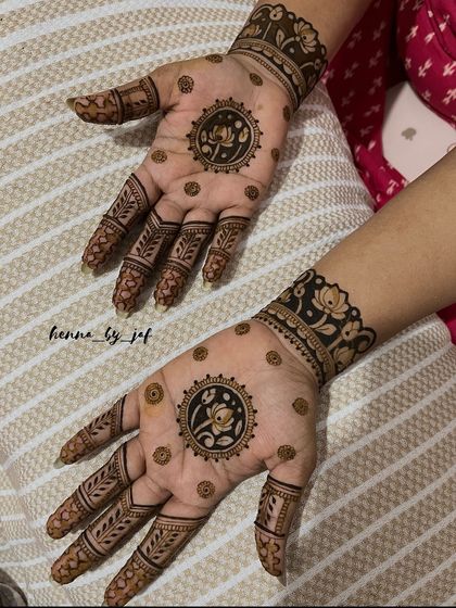 A stunning bridal design with a central lotus mandala on each palm. The fingers feature leafy patterns, and the wrists are adorned with thick, floral bands, creating a balanced and elegant look.
