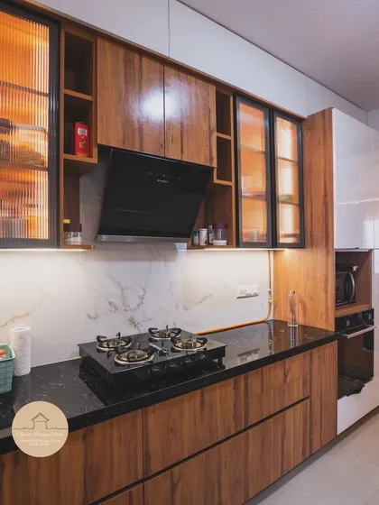 A kitchen built for real life. This contemporary kitchen features a mix of warm wood and glossy white laminate finishes, with fluted glass cabinets and integrated lighting. We designed it with a built-in oven and microwave unit for a seamless look and a practical workflow.