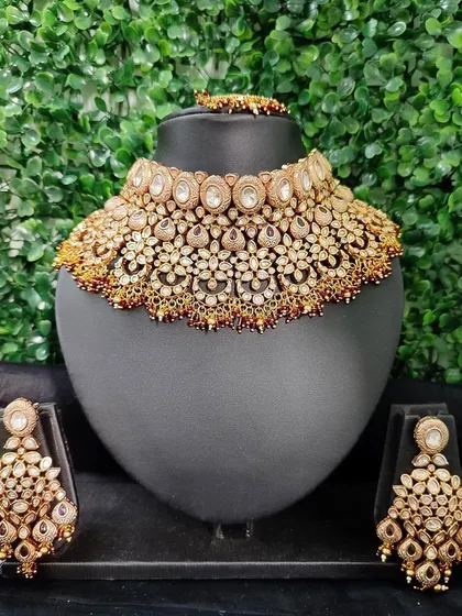 A stunningly detailed and wide kundan choker set, perfect for a bride who wants a bold and traditional look. The set includes the necklace and matching chandelier earrings.