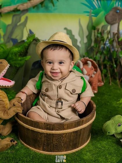 A smiling baby explorer surrounded by his friendly dinosaur companions.