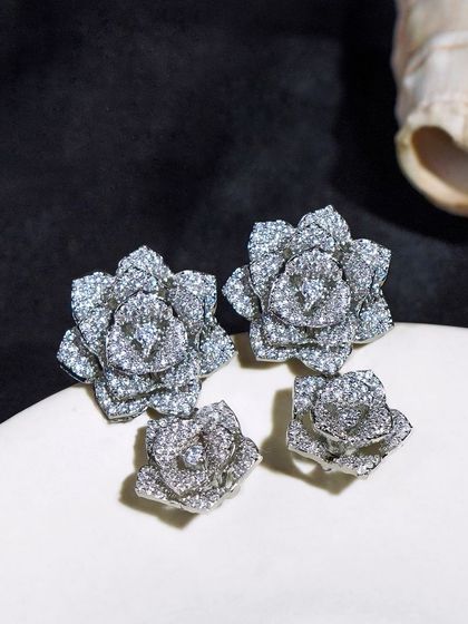 A pair of statement silver floral earrings, shot with a dark, moody aesthetic. This style of photography can give a brand a more luxurious and high-end feel.