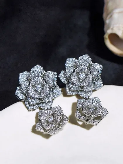 A pair of statement silver floral earrings, shot with a dark, moody aesthetic. This style of photography can give a brand a more luxurious and high-end feel.