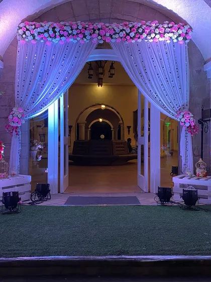 A simple yet elegant entrance decoration. We used sheer white curtains with sequin details, accented with pink and white floral arrangements, to create a soft and romantic entryway for a reception.