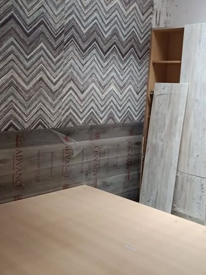 Another view of the bedroom work in progress, showing the textured wallpaper and initial furniture placement. Our team's dedication ensures projects move forward, even on weekends.