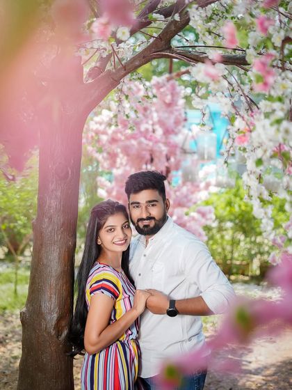A closer portrait under the blossoms, focusing on the couple's happy expressions. The flowers create a beautiful natural frame around them.