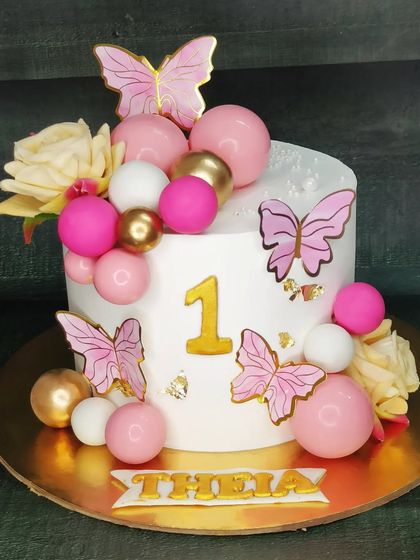 A beautiful butterfly-themed cake for a one-month celebration. This chocolate roasted almond cake is decorated with pink and gold butterflies and spheres.