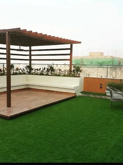 A simple yet effective rooftop design. We installed a pergola with built-in seating over a wooden deck, surrounded by a large expanse of low-maintenance artificial turf, perfect for an urban environment.