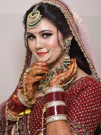 A close-up on the details. This shot highlights the beautiful craftsmanship of the rental jewellery, including the nath and the intricate necklace, against the maroon bridal lehenga.