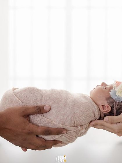 A precious newborn held gently in the hands of their parents, symbolizing the beginning of their family's journey.