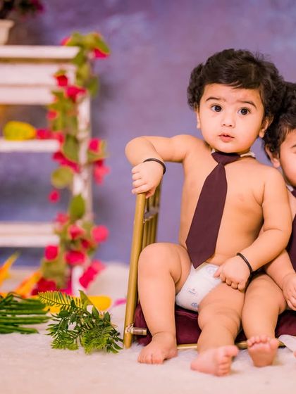 A simple and sweet setup for twin boys. The matching ties and chairs against a soft purple backdrop create a classic and heartwarming portrait.