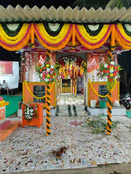 This image shows the complete setup for the Maghi Ganpati pandal, including the decorated entrance pillars and the traditional flower garlands that define the festive space.