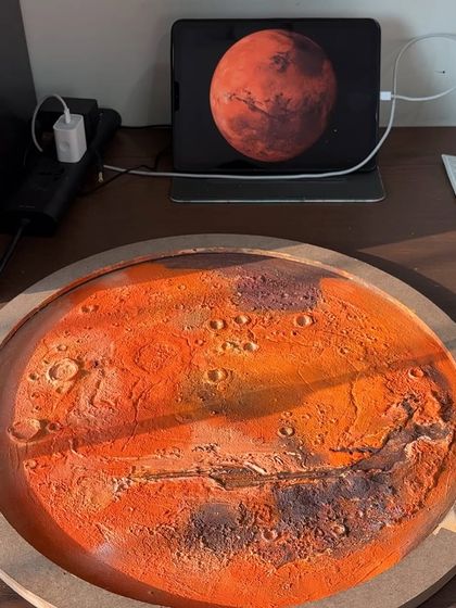 My workspace, with the painted Mars lamp next to its inspiration on my tablet. I use reference images to get the details just right for each custom planetary piece.