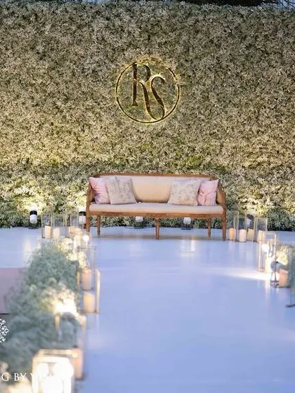 An elegant all-white reception stage, featuring a lush wall of baby's breath and a custom monogram for the couple. This design proves that simplicity can be the ultimate sophistication, creating a timeless and romantic backdrop.