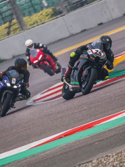 Three riders in close formation, including a Yamaha R15 and a Ducati Panigale, navigate the colored kerbs of the track. This demonstrates how our riders learn to handle different machinery in a competitive setting.
