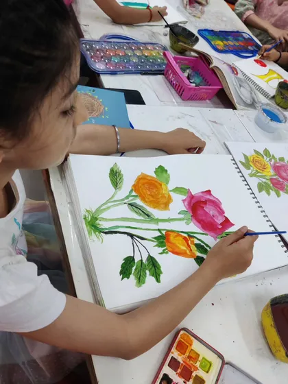 A young student is captured painting a bouquet of roses, learning wet-on-wet and layering techniques in watercolor.
