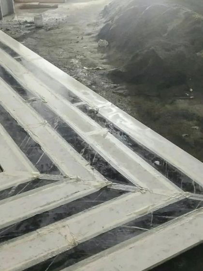 This modern kitchen and dining area is defined by its luxurious materials. A geometric chandelier hangs over a marble-topped dining table, while the sleek, handleless cabinetry and integrated appliances create a clean, contemporary look.
