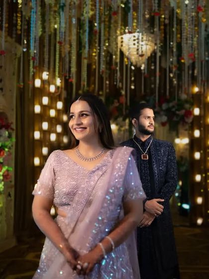 A beautiful portrait of the couple standing in a grand, beautifully decorated wedding hall. The lighting and decor add a magical feel to their moment.