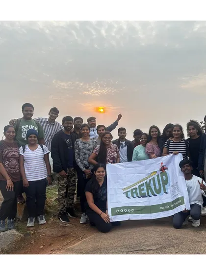 A group photo with the Trekup banner during a beautiful sunrise on the Huthridurga trek.