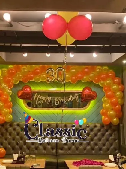 A vibrant birthday party setup in a restaurant, featuring a balloon arch and ceiling decor. We also handle private milestone celebrations hosted in commercial venues.