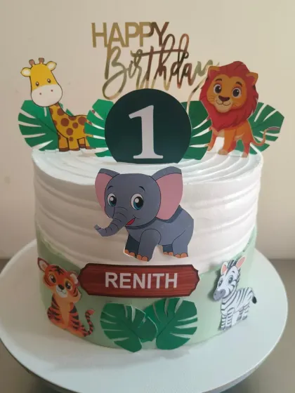 A cute jungle animal cake for a first birthday, decorated with non-fondant printed toppers of a lion, giraffe, elephant, and more. A great option for a vibrant look.