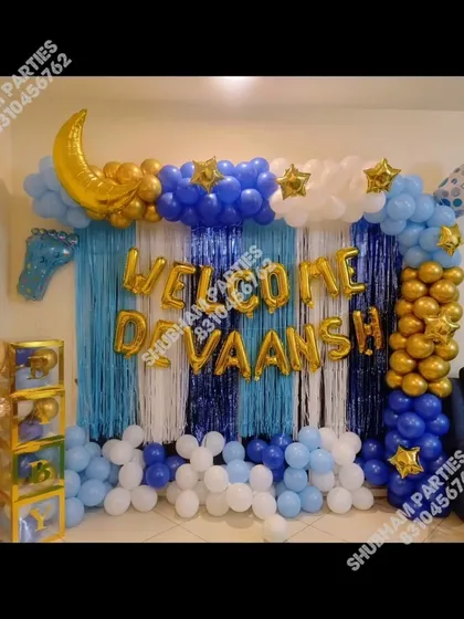 A "Welcome Devansh" home decoration with a blue and gold balloon frame and baby-themed props.