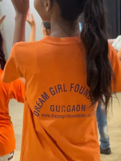 A close-up of the 'Dream Girl Foundation Gurgaon' logo on the back of a child's t-shirt during our community dance event.