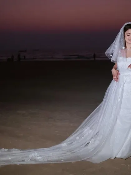 A full-length portrait showcasing the bride's stunning wedding gown with its long, elegant train on the beach. A perfect shot for a destination wedding.