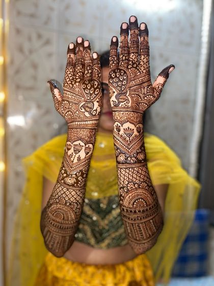 A playful pose showing off a traditional design with prominent peacock and elephant motifs on the palms and arms.