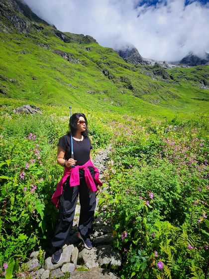 Exploring the Valley of Flowers in Uttarakhand. For trekking, I advise practical clothing like these track pants and a bright pink jacket for visibility and a pop of color against the green landscape.