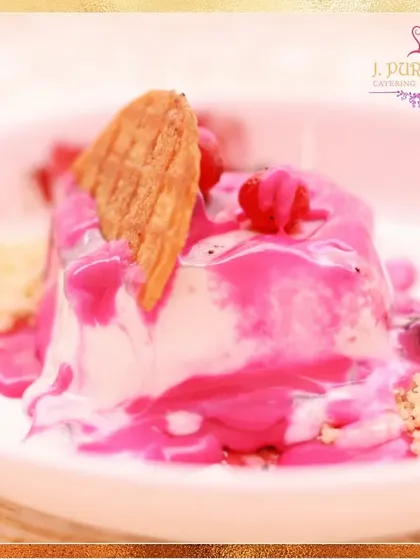 This vibrant dessert features a creamy panna cotta base topped with a bright pink berry sauce and a delicate wafer. It's a visually appealing and delicious option.