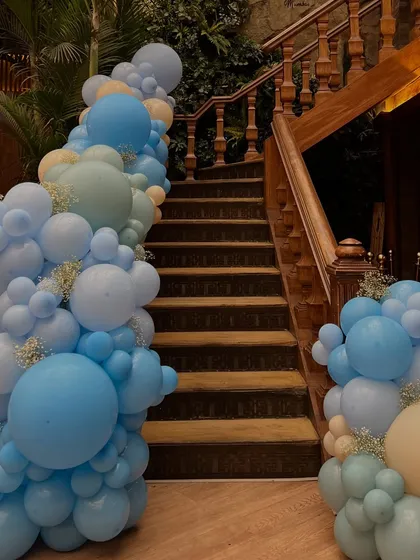A stunning balloon garland in shades of blue, cream, and mint cascaded down the staircase, creating a grand and festive entrance for the baby celebration.