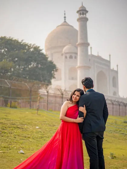 A tender pose with the bride leaning on her partner's shoulder, both looking out at the view of the Taj Mahal.